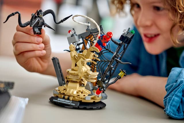 Child playing with a LEGO Super Heroes Marvel: Epic Battle: Spider-Man vs. Sandman set on a table