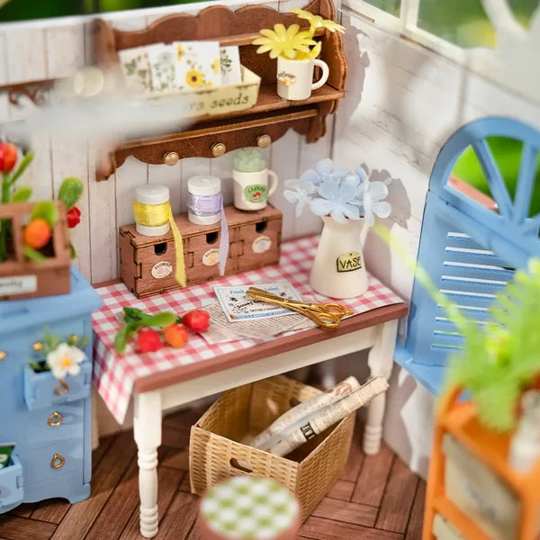 Sweet Sips Tea DIY Miniature House with wooden shelves, table, and various items on a checkered tablecloth.