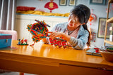 Child playing with colorful LEGO Chinese Festivals: Fortune Firecracker at a table in a room with decorations.