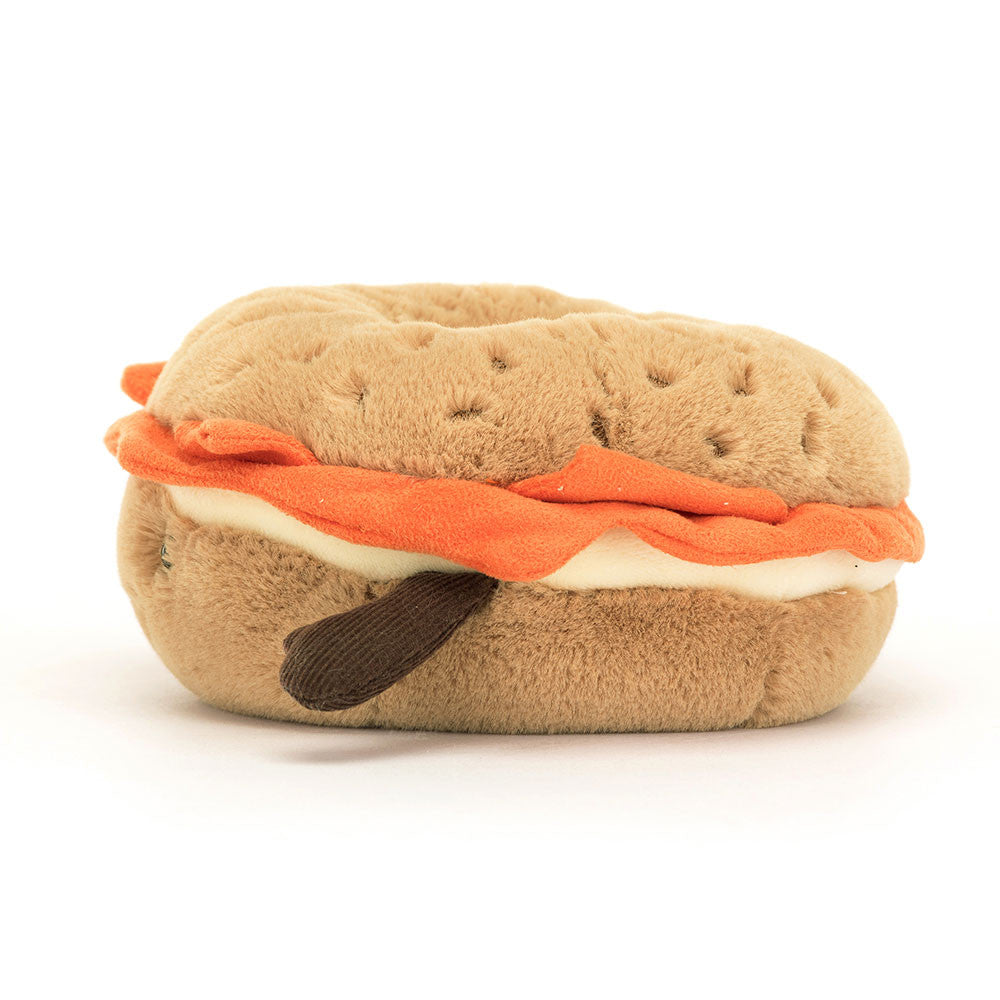 Side view of a plush Amuseables Bagel toy with brown arms on a white background