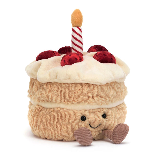 Soft plush toy resembling a cheerful layered cake with white frosting, red cherries on top, a striped candle, and small feet, named Amuseables Birthday Cake.
