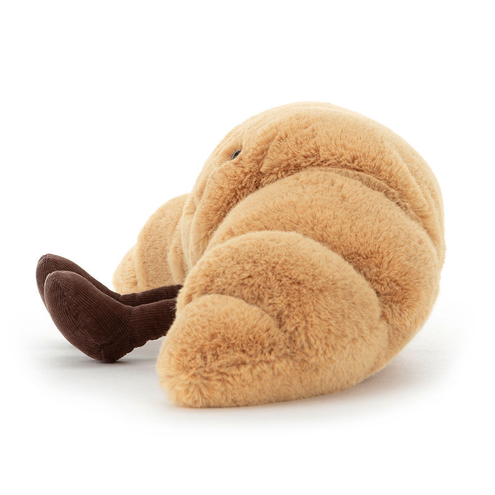Side view of a plush toy Amuseables Croissant with brown legs on a white background