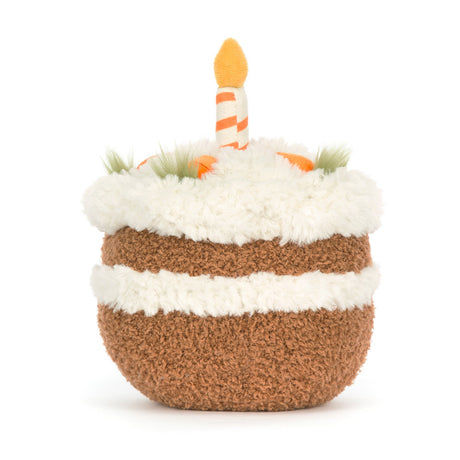 Soft plush Amuseables Carrot Cake toy designed to look like a layered birthday cake with white frosting, carrots, greenery accents, and a striped candle on top.