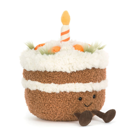 Soft plush toy designed as a smiling slice of Amuseables Carrot Cake with a fluffy white frosting layer, green carrot tops, and a single striped candle on top.