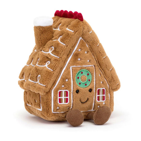 Soft plush toy shaped like a smiling gingerbread house with white icing details, red window panes, a green wreath, and a chimney, named Amuseables Gingerbread House.