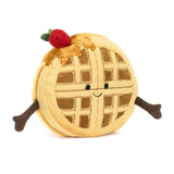 Amuseables Rene Waffle is a soft plush toy shaped like a round waffle with a smiling face, outstretched arms, syrup drizzle, and a small red strawberry on top.