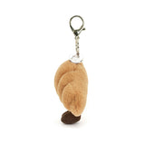 Side view of a plush Amuseables Croissant Bag Charm on a white background