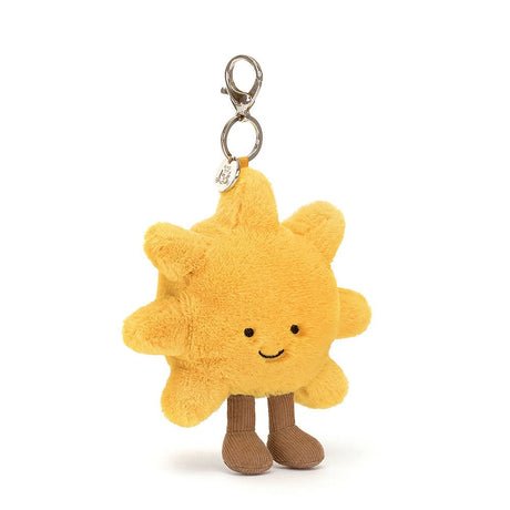 Amuseables Sun Bag Charm is a soft, plush yellow sun with smiling face and brown corduroy legs, featuring a metal clasp for attaching to bags or keys.