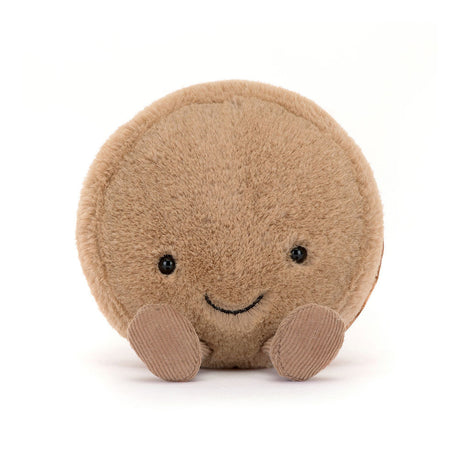 Amuseables Mona Macaron is a soft, round plush toy with a friendly smiling face and small corduroy feet, perfect for a kid's birthday gift or toddler toy.