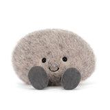 Soft and fluffy plush toy in the shape of a smiling pebble with small black eyes and gray feet, designed as the Amuseables Pebble for kids and collectors.