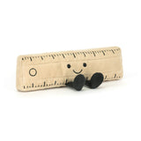 Soft plush toy shaped like a beige ruler with black measurement markings, a smiling face, and small black feet sitting upright, called Amuseables Ruler.