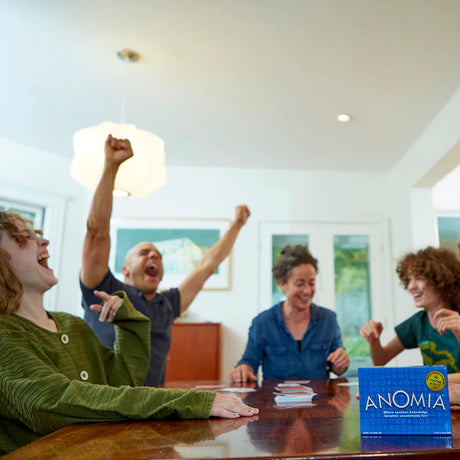 People playing a board game together with 'ANOMIA' box on a table.