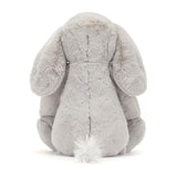 Plush grey stuffed animal with long floppy ears and a fluffy tail, shown from the back, designed as Bashful Luxe Elephant Thuddeus, a soft toddler toy.