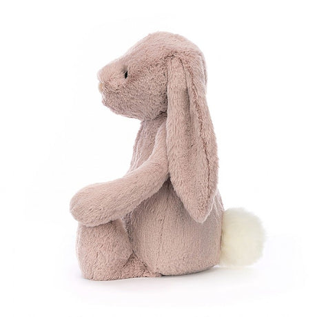 Soft pink plush stuffed bunny with long ears and a white fluffy tail, sitting upright in profile, Bashful Luxe Bunny Rosa Huge baby toy perfect for cuddling.