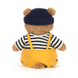Bartholomew Bear Seafarer Outfit dressed teddy bear wearing a navy blue knit hat, striped shirt, and mustard yellow overalls , viewed from the back.