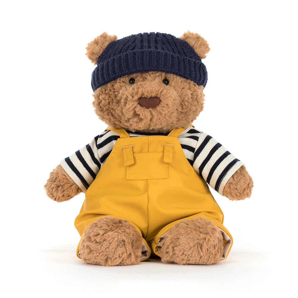 Bartholomew Bear Seafarer Outfit dressed teddy bear wearing a navy knit hat, striped shirt, and bright yellow overalls, perfect as a cuddly stuffed animal or kids dress-up toy.