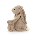 Soft plush beige bunny with long floppy ears and a fluffy white tail, shown sitting sideways, Bashful Beige Bunny Large stuffed animal perfect for children’s play and comfort.