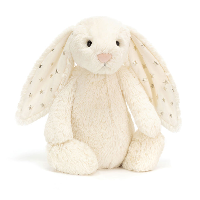 Bashful Twinkle Bunny is a soft cream-colored plush rabbit with long ears lined with fabric featuring silver star patterns, perfect as a cuddly toddler toy or gift.