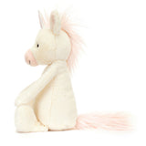 Side view of a soft, cream-colored plush unicorn with a light pink mane and tail sitting upright, featuring the Bashful Unicorn Medium.