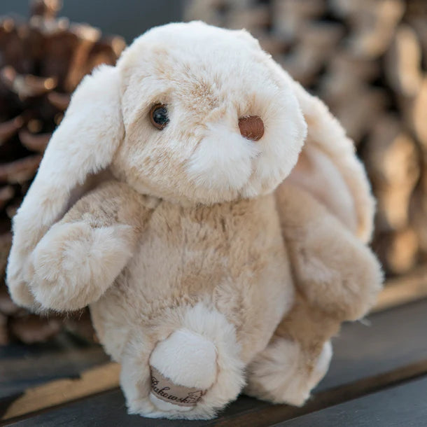Plush Kanini - Taupe bunny toy with a blurred background of pinecones