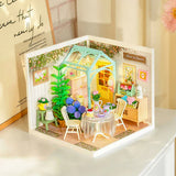 Miniature model of a cozy room with furniture and decor, illuminated from within.
