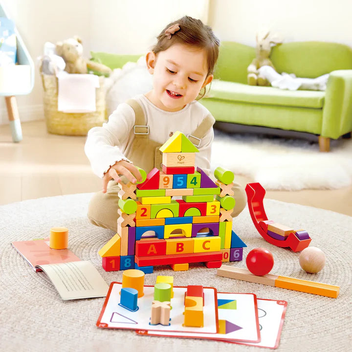 Child playing with colorful wooden Grow With Me Blocks in a living room.