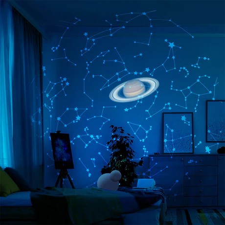 Room with a starry night sky projection on the wall, featuring constellations and Saturn.