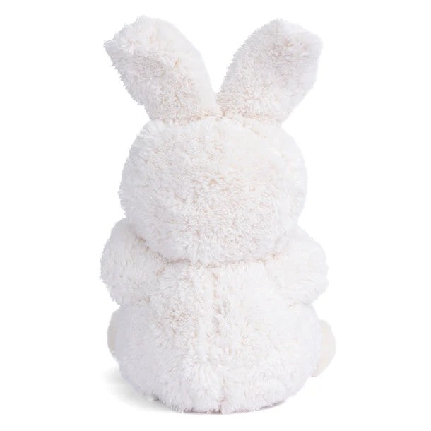 Plush toy bear dressed as a rabbit in a white outfit on a white background