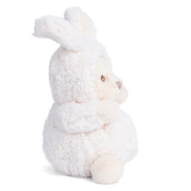 Plush toy bear dressed as a rabbit in a white outfit on a white background