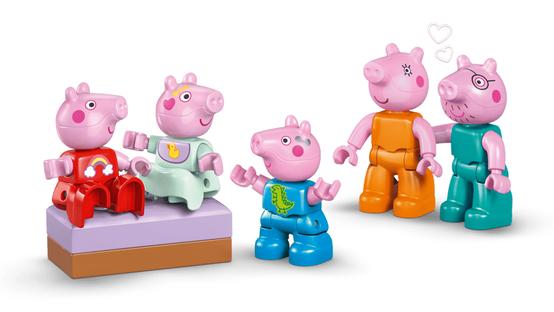 Five pink toy pigs in colorful outfits on a green background