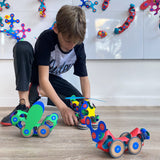 Child playing with colorful Wheel Creator Pack on a wooden floor.