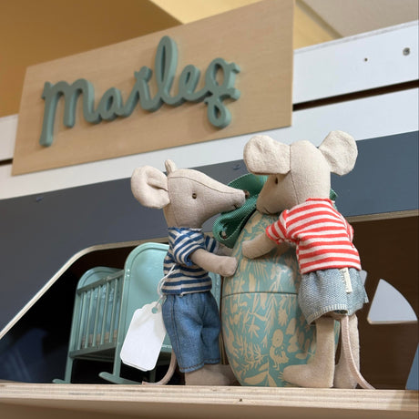 Two toy mice with an easter egg in front of a Maileg sign