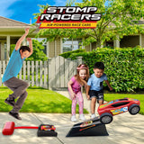 Children playing with Stomp Racers toy cars on a driveway in front of a house.