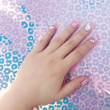 Hand with colorful nail art on a pastel blue and pink leopard print background