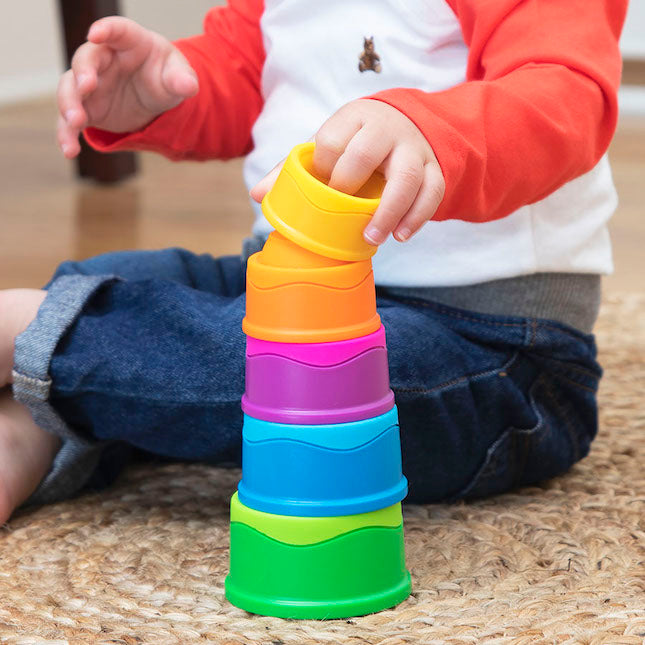 Child playing with colorful Dimpl Stack on a wooden floor