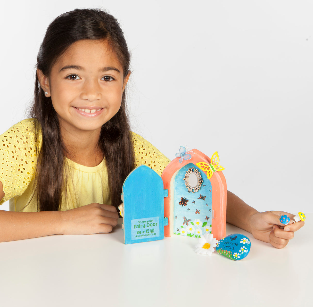 Young girl with a Butterfly Fairy Door set on a white background