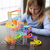 Child playing with a colorful Trestle Tracks Deluxe Set indoors.