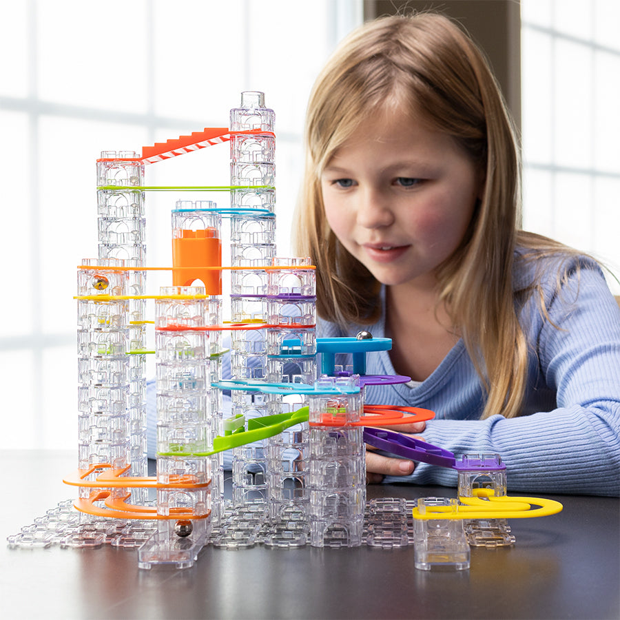 Child playing with a Trestle Tracks Deluxe Set on a table.
