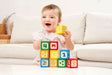 Baby playing with colorful Grip-n-Stack Silicone & Wood Blocks on a couch