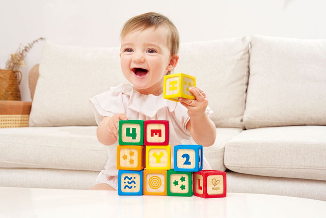Baby playing with colorful Grip-n-Stack Silicone & Wood Blocks on a couch