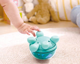 Child's hand interacting with a Twist & Tune Turtle toy on a carpeted floor.