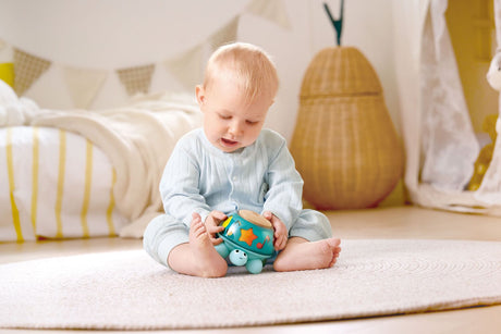Baby playing with a colorful Twist & Tune Turtle toy on a carpeted floor.