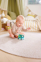 Baby playing with a Twist & Tune Turtle toy on a carpeted floor in a cozy room.