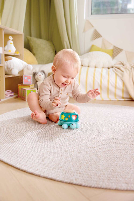 Baby playing with a Twist & Tune Turtle toy on a carpeted floor in a cozy room.