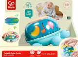 Hape Twist & Tune Turtle toy with packaging and baby playing with it
