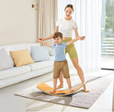 Woman assisting a child on a Light-Up Balance Board in a living room.