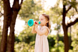 Child playing with a Musical Maestro Trumpet (Pixelz) outdoors with a blurred natural background