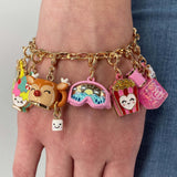 Gold chain bracelet with colorful charms on a wrist against a neutral background
