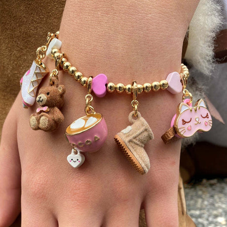 Bracelet with various charms including a teddy bear, cup, and boot on a wrist.