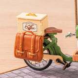 Toy bike with a wooden box labeled 'Street Coffee' and a brown leather bag on a beige background included with the e Aromatic Coffee Cart kit.